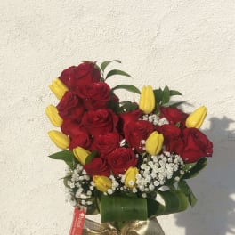 Bouquet of red roses and yellow tulips in a glass vase