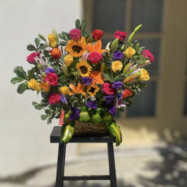 Colorful mixed bouquet with roses, sunflowers, and lilies in a basket