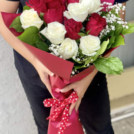 Bouquet of red and white roses wrapped in pink paper with a polka-dot ribbon