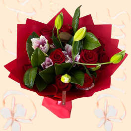 Bouquet of red roses and pale lilies wrapped in red paper