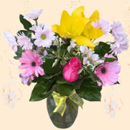 Bouquet of pink and lavender daisies with a yellow lily in a vase