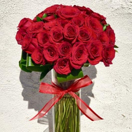 Bouquet of red roses in a clear glass vase with a red ribbon