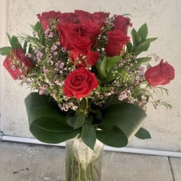 Bouquet of red roses with pink filler flowers in a clear glass vase