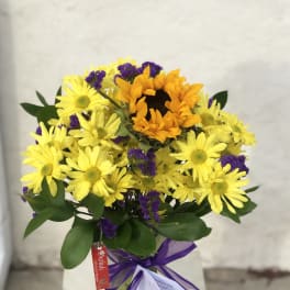 Yellow daisies and an orange sunflower bouquet in a glass vase