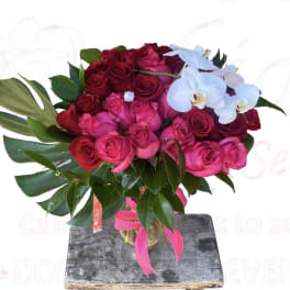 Bouquet of red and pink roses with white orchids in a glass vase