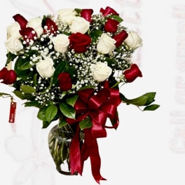 Bouquet of red and white roses in a glass vase with a red ribbon