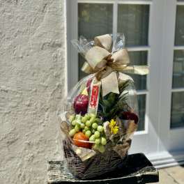 Gift basket with fruit and a ribbon bow wrapped in clear cellophane