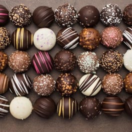 Assorted chocolate truffles arranged in rows on a flat surface