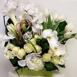 White orchids, roses, and tulips arranged in a green box