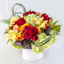 Bouquet of red roses, yellow orchids, and green hydrangeas in a white vase