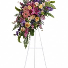 Tall floral spray with pink lilies, roses, and purple flowers on a white stand