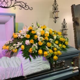 Large yellow and white floral spray on a casket