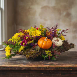 Fall floral arrangement with pumpkins on a bark base