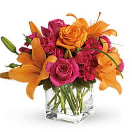 Orange lilies and pink roses arranged in a clear glass vase