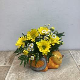 Yellow daisies and white daisies arranged in a cat-shaped ceramic container
