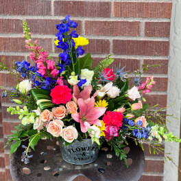 Colorful mixed bouquet in a metal container with roses and lilies