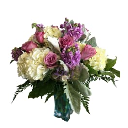 Pink roses and purple flowers arranged in a blue glass vase