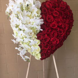 Heart-shaped floral display of red roses and white orchids on an easel