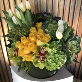 Yellow roses and white tulips in a round black container