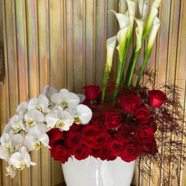 Red roses and white orchids in a white vase with tall calla lilies