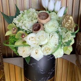 White roses and tulips arranged in a black vase with gold accents