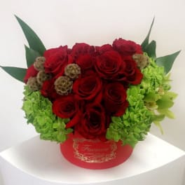 Red roses and green hydrangeas in a red round box