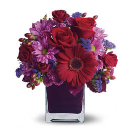 Red and purple mixed bouquet in a square glass vase