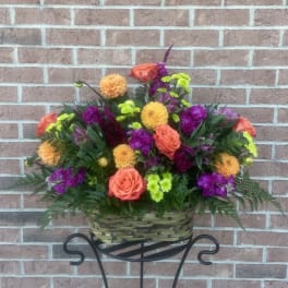 Basket of orange roses and purple flowers on a stand