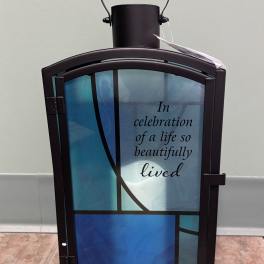 Decorative memorial lantern with blue glass panels and a sympathy message
