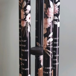 Black hanging wind chime with floral-printed tubes and a round top