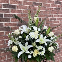 White lilies and roses in a basket arrangement with white daisies