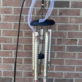 Black wind chime with silver tubes and a white ribbon bow
