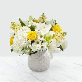 White and yellow flower arrangement in a woven vase
