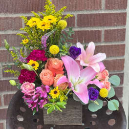 Mixed bouquet with pink lilies, roses, and yellow daisies in a wooden box