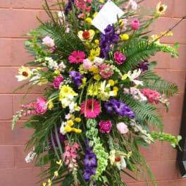 Tall standing floral spray with mixed bright flowers and greenery