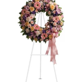 Pastel floral wreath on a white easel with pink ribbon