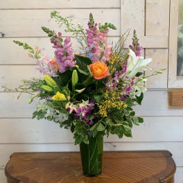 Mixed bouquet with roses, lilies, and snapdragons in a green vase