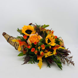 Autumn cornucopia with yellow sunflowers and orange roses in a woven horn basket