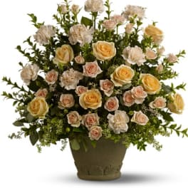 Large arrangement of cream and peach roses and carnations in a stone-colored pot