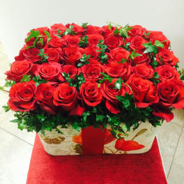 Red roses arranged in a rectangular gift box with ivy accents