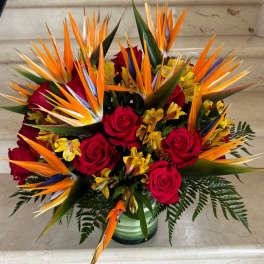 Bouquet of red roses and orange bird of paradise in a glass vase