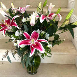 Pink and white lilies arranged in a glass vase