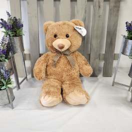 Large teddy bear with a checkered bow, flanked by small purple flower arrangements
