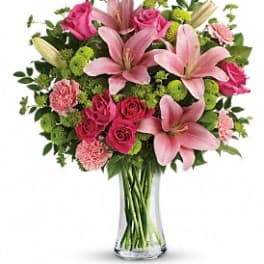 Pink lilies, roses, and carnations in a clear glass vase