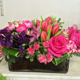 Pink and purple mixed flower arrangement in a black rectangular vase
