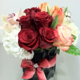 Bouquet of red roses, white hydrangea, and peach tulips in a black vase