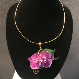 Pink orchid corsage on a gold wire necklace display