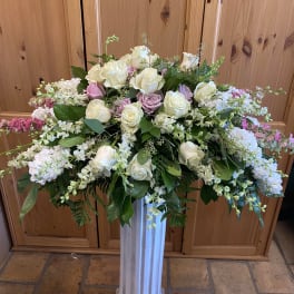 Large white and blush rose arrangement in a tall pedestal vase