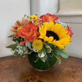 Bouquet of sunflowers, roses, and mixed blooms in a glass vase