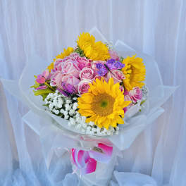Bouquet of pink roses and yellow sunflowers wrapped in white paper